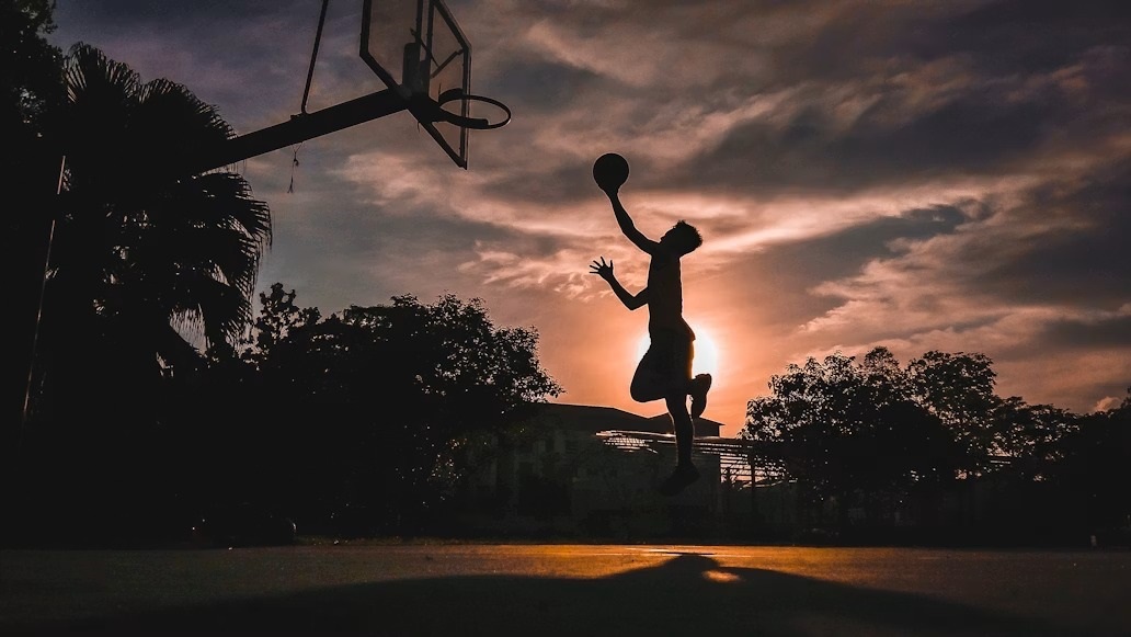 Athlete dunking at sunset